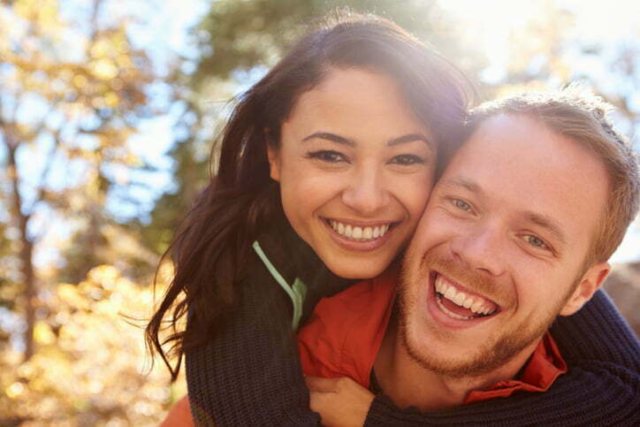 Backlit portrait of mixed race couple embracing in a forest