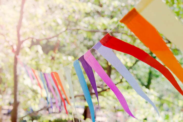 Close up of a colorful party banner tied between trees in a park at an open air celebration event.