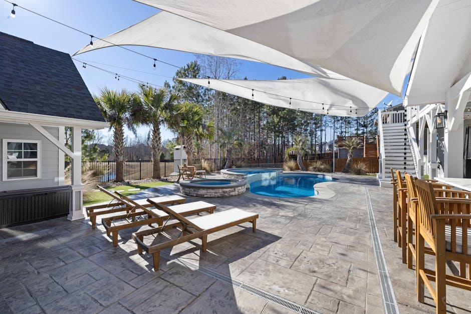 Outdoor fabric shade sail stretched over a Florida patio with lounge chairs and tropical landscaping