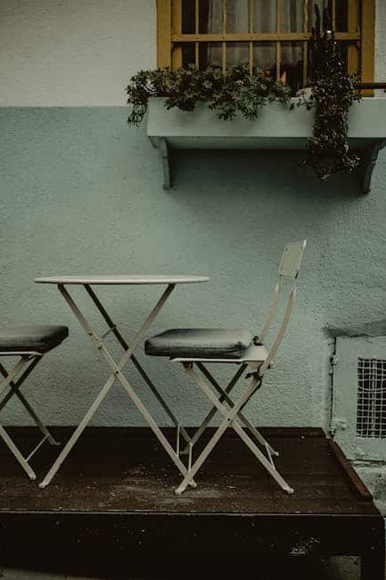 Small Florida garden apartment balcony with folding bistro chairs and a vertical planter in morning light