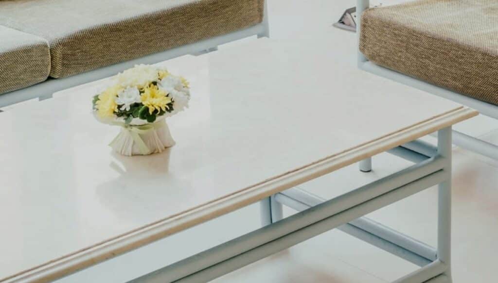 White PVC style patio table frame resting on tile