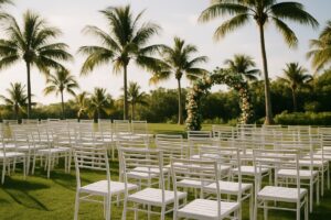 Rows of white powder-coated aluminum stacking chairs set up for an outdoor Florida wedding ceremony