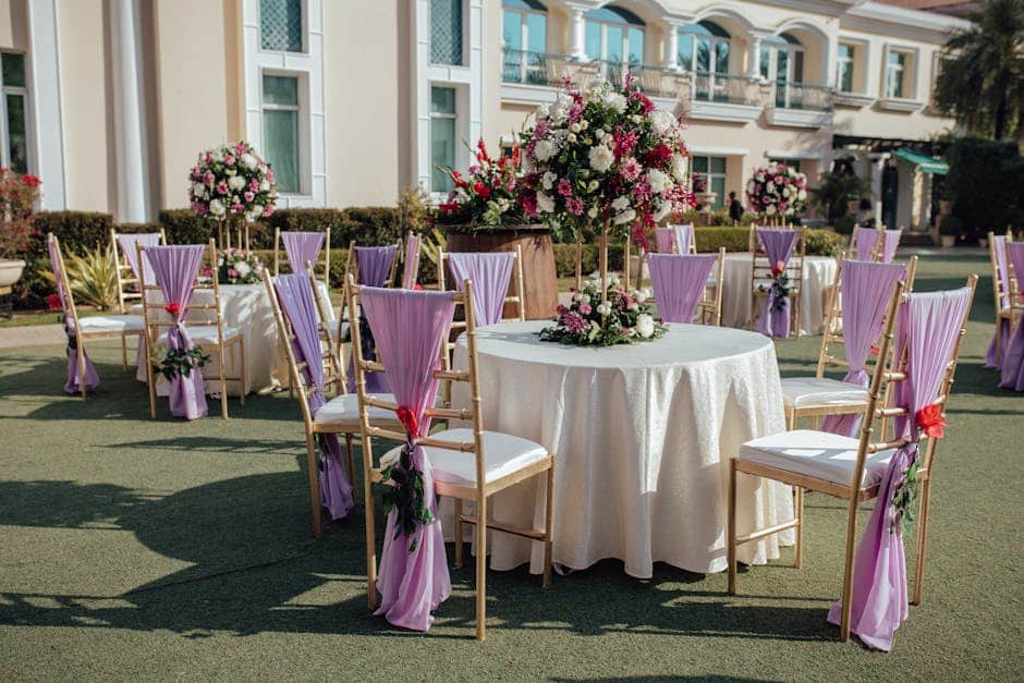 Close-up of champagne-finish aluminum stack chairs at a Florida garden wedding reception with floral centerpieces