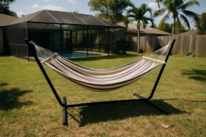 Fabric hammock on a freestanding steel stand in a Florida backyard with a screened pool enclosure and palms