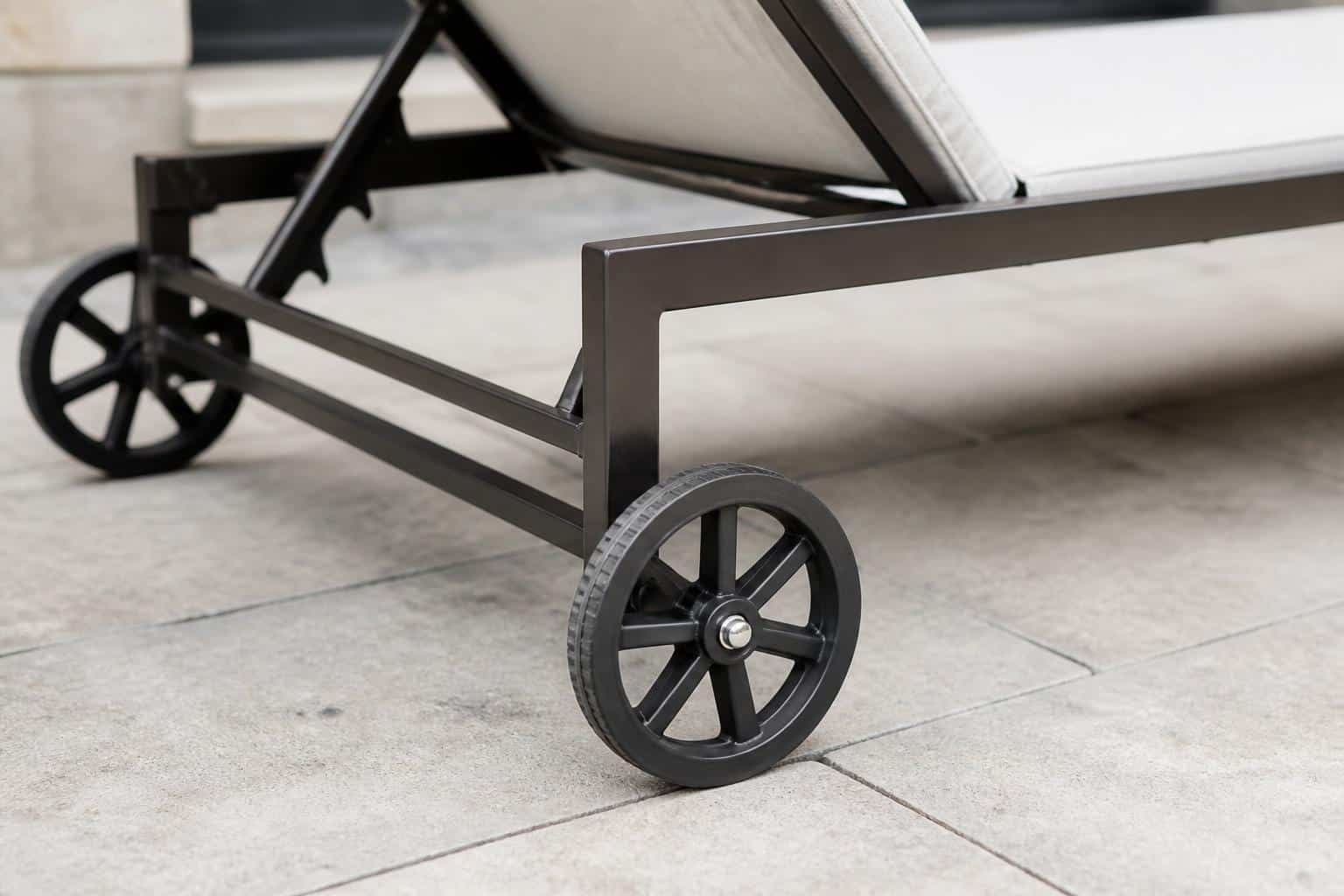 Aluminum chaise lounge with rear wheels positioned near a Florida pool deck