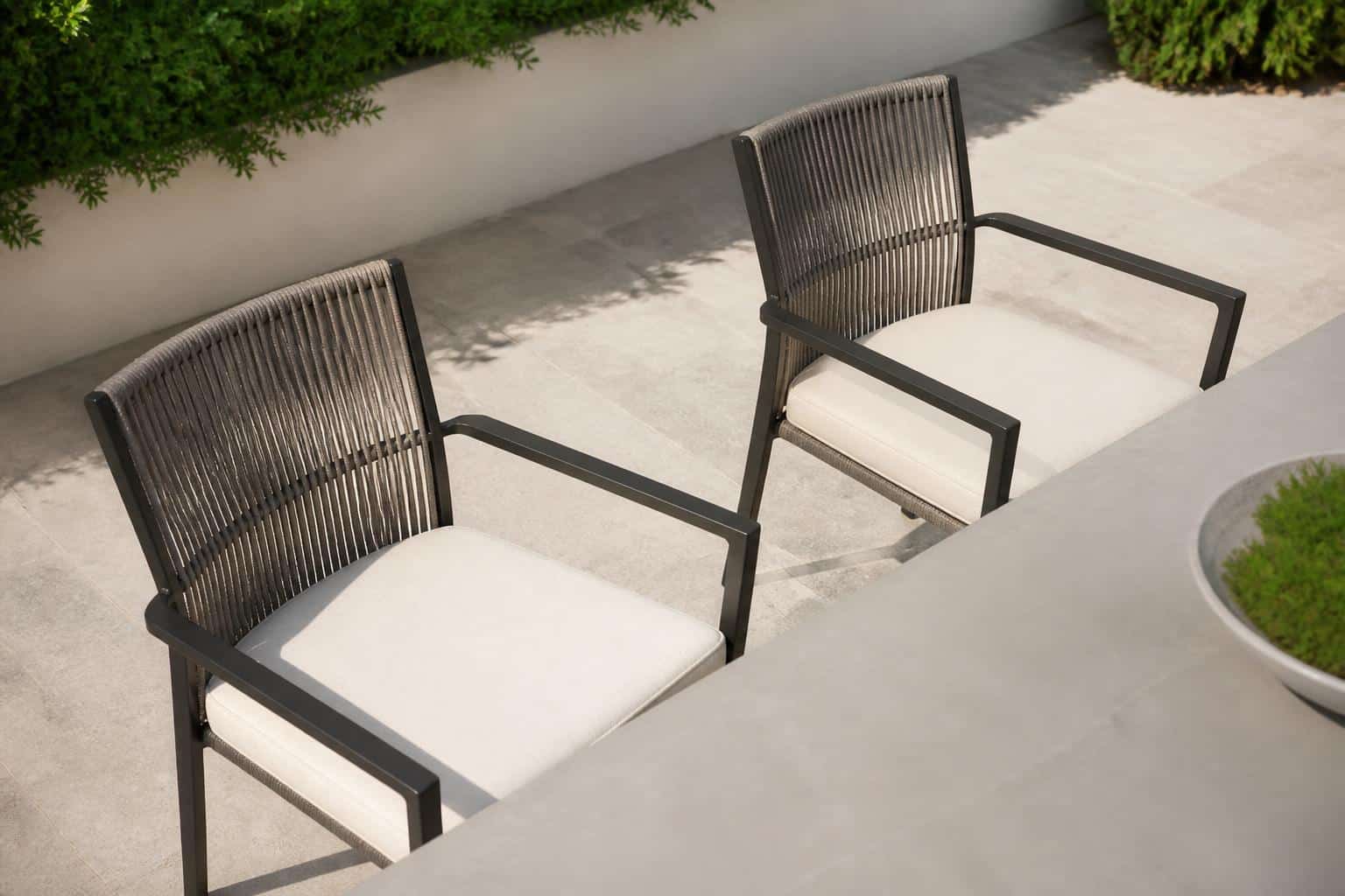 Outdoor dining set with arm chairs spaced evenly along a rectangular table on a covered lanai