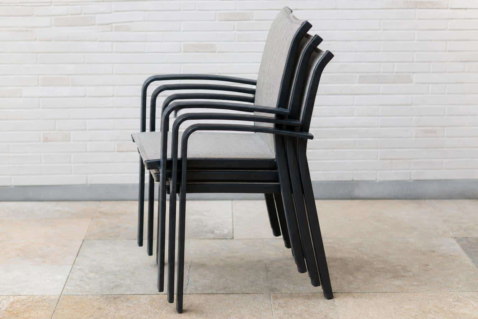 A neat stack of aluminum patio chairs tucked against a lanai wall