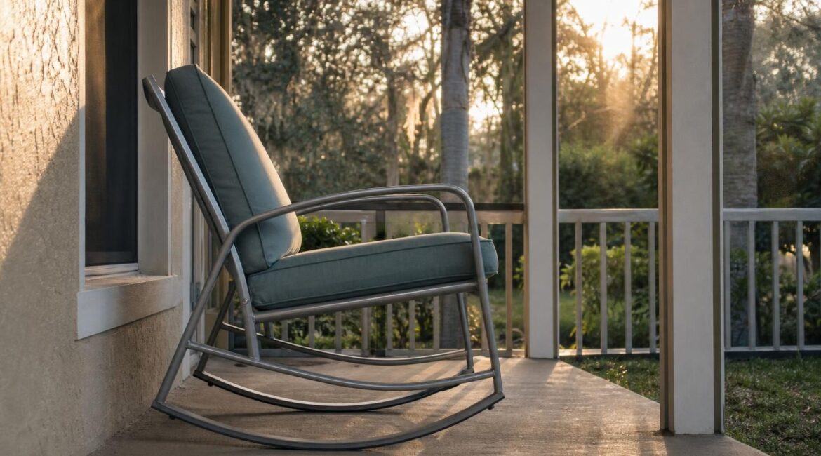 An aluminum-frame outdoor rocking chair with a cushioned seat on a Florida porch, side profile showing the curved base mechanism