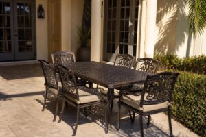 A matched set of powder-coated bronze aluminum patio chairs and a dining table on a Florida patio in bright afternoon light