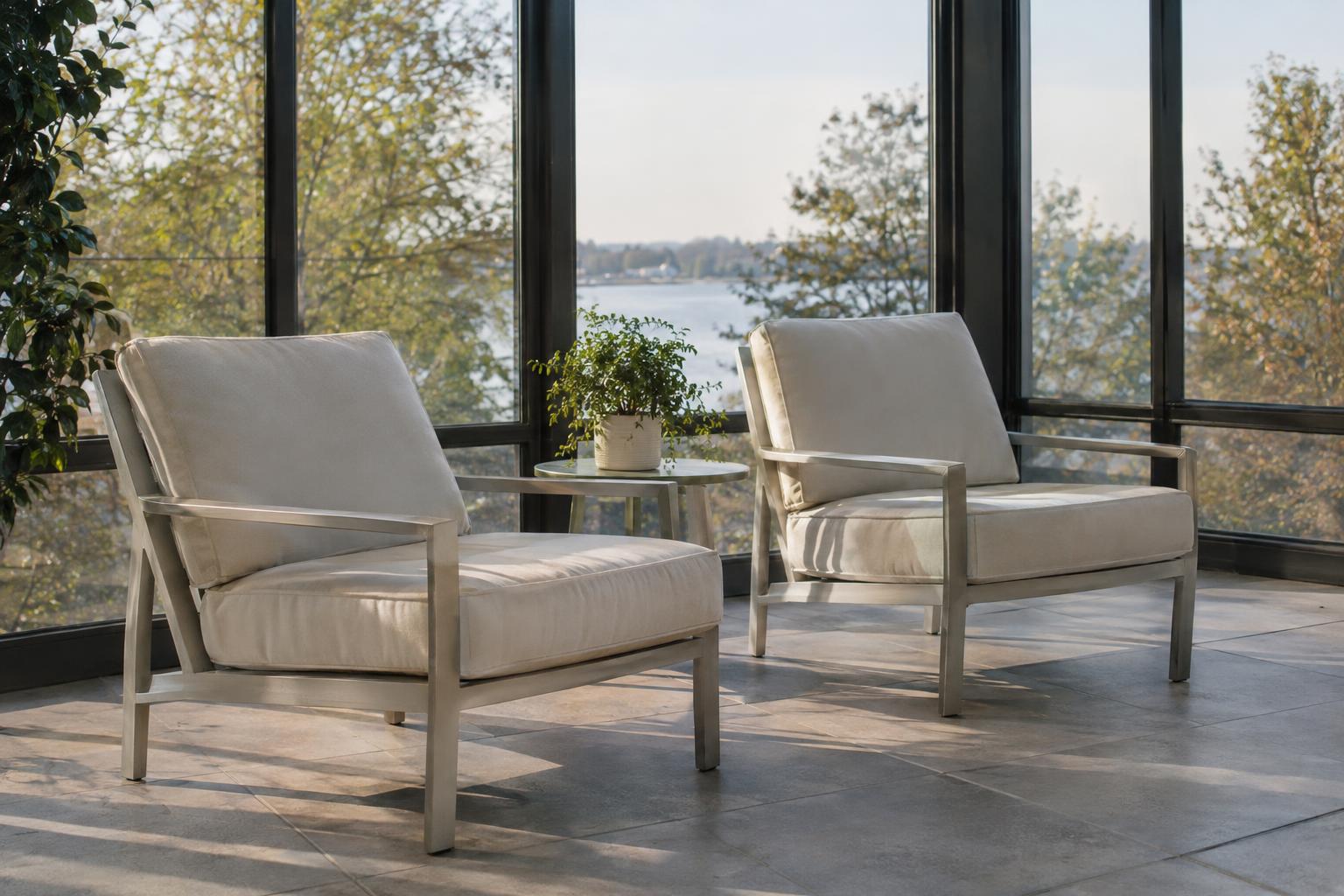 Two cream-cushioned lounge chairs on a tile floor in front of tall windows in a sunroom